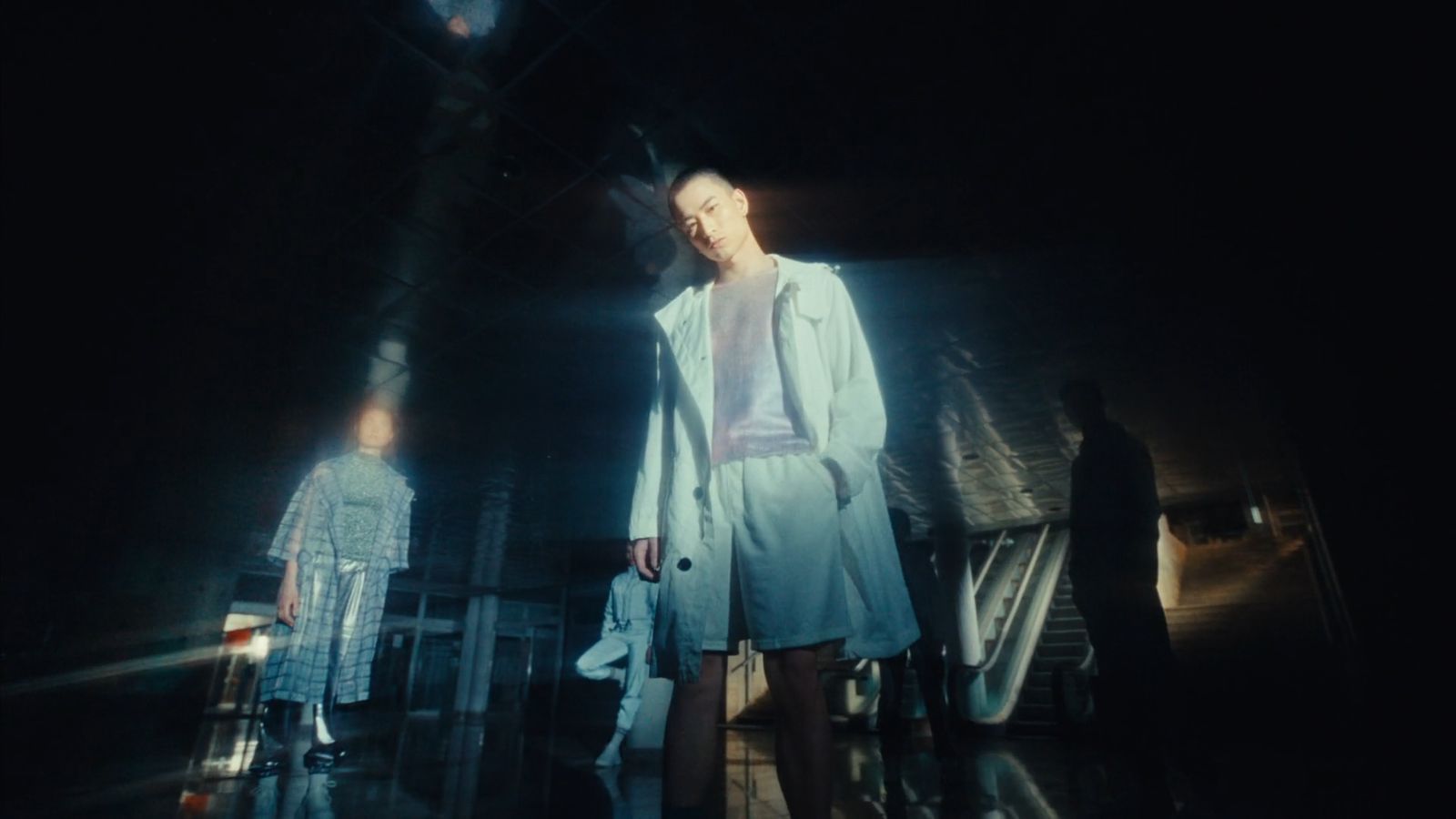 a woman is walking down a runway in a white coat