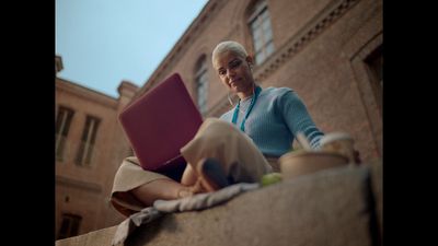 a woman sitting on a ledge using a laptop computer