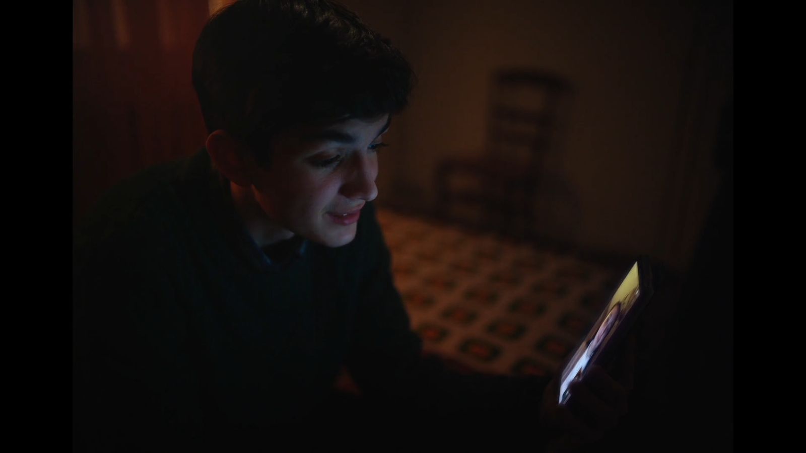 a young boy looking at a book in the dark