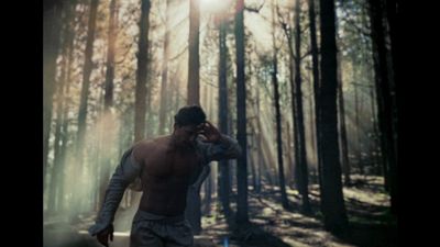 a man walking through a forest while talking on a cell phone