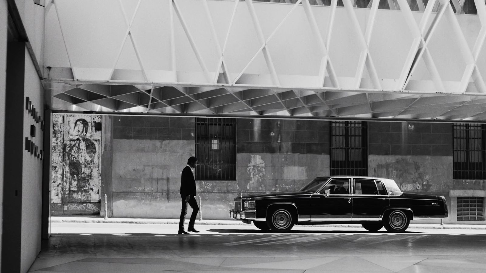 a black and white photo of a man standing next to a car