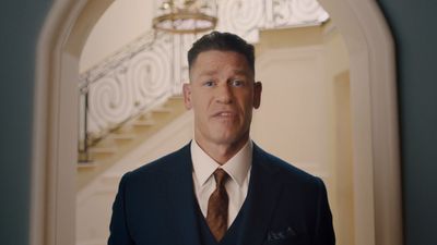 a man in a suit and tie standing in front of a staircase