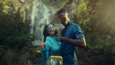 a man and a woman standing in front of a waterfall