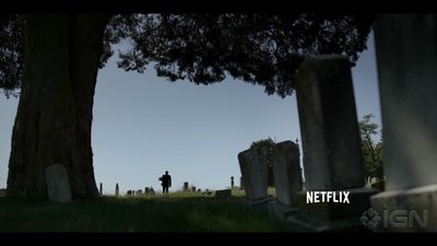 a man standing in a cemetery next to a tree