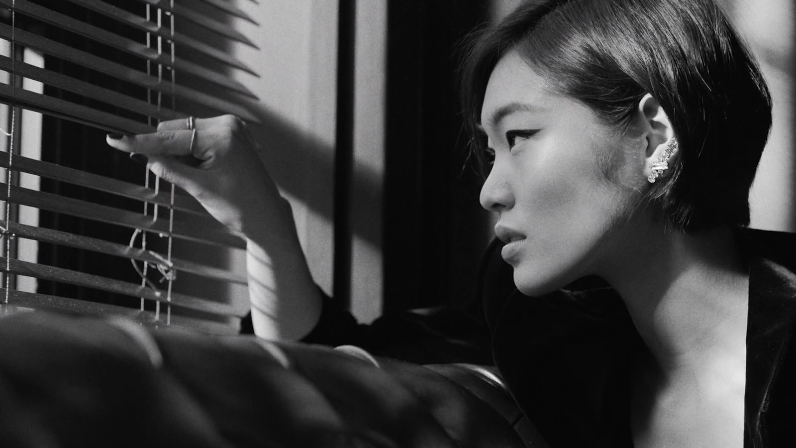 a black and white photo of a woman looking out a window