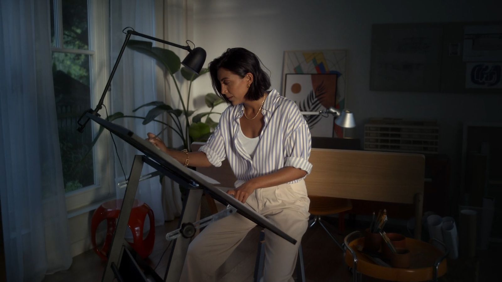 a woman sitting in a chair working on a piece of art