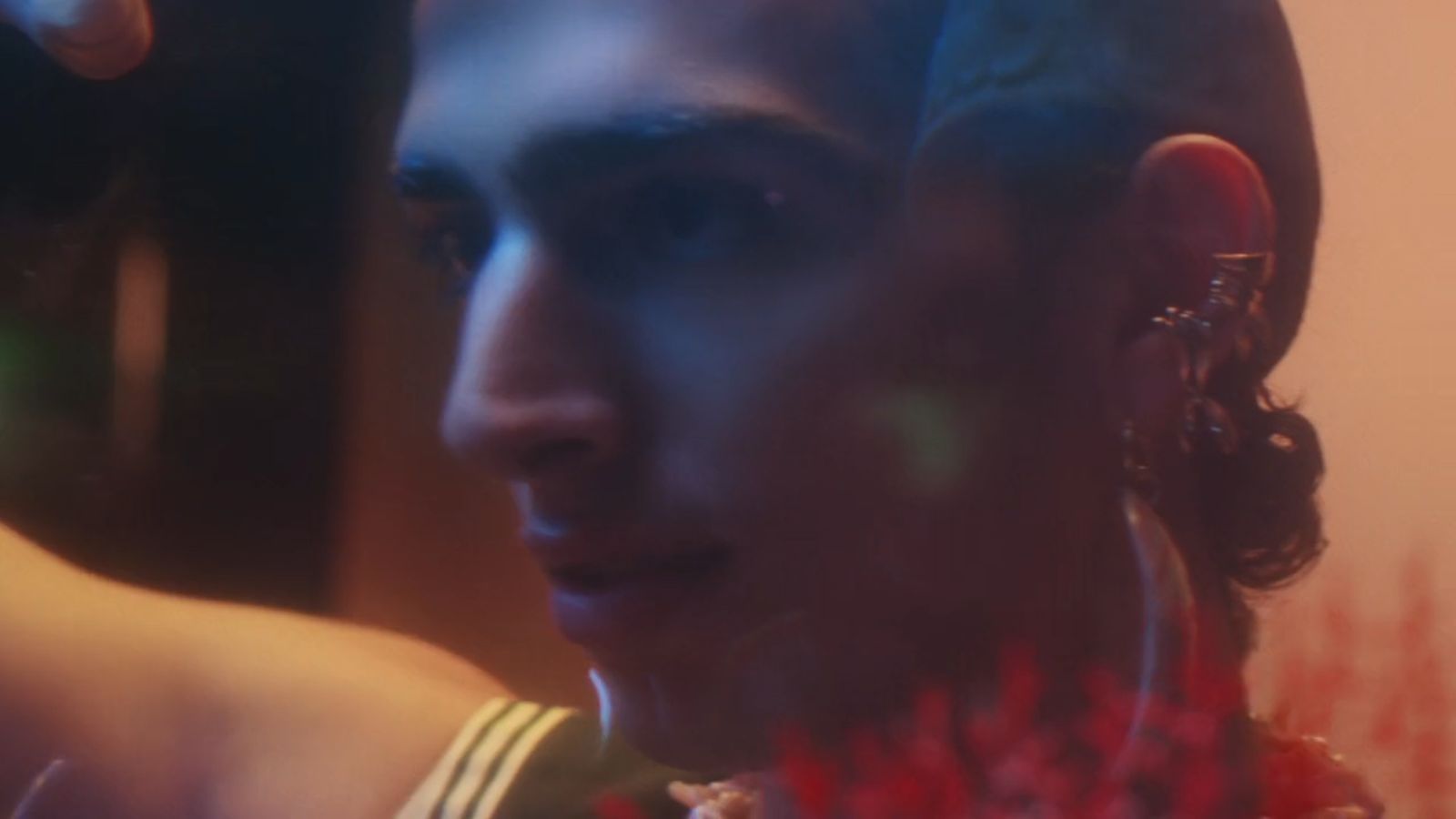 a man wearing a necklace and earrings in a room