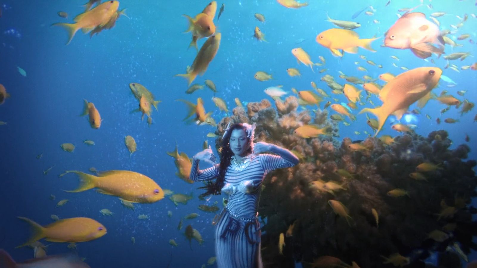 a woman standing under a large group of fish