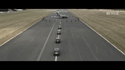 a long line of cars driving down a runway