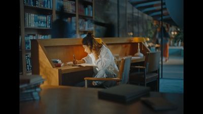 a woman sitting at a table in front of a book shelf