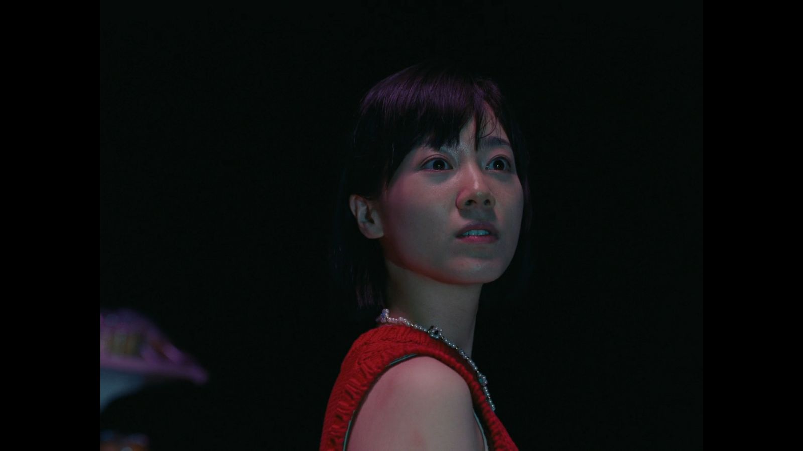 a woman in a red dress standing in the dark