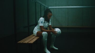 a woman sitting on a bench holding a soccer ball