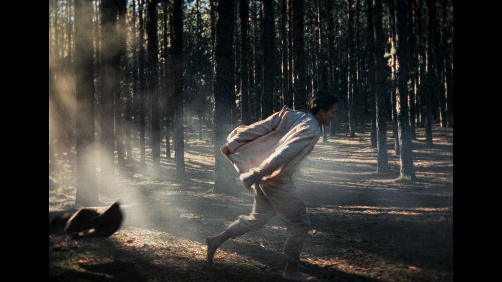 a man is running through the woods with a jacket on