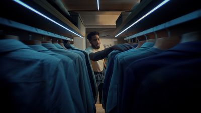 a man is looking through a row of blue shirts