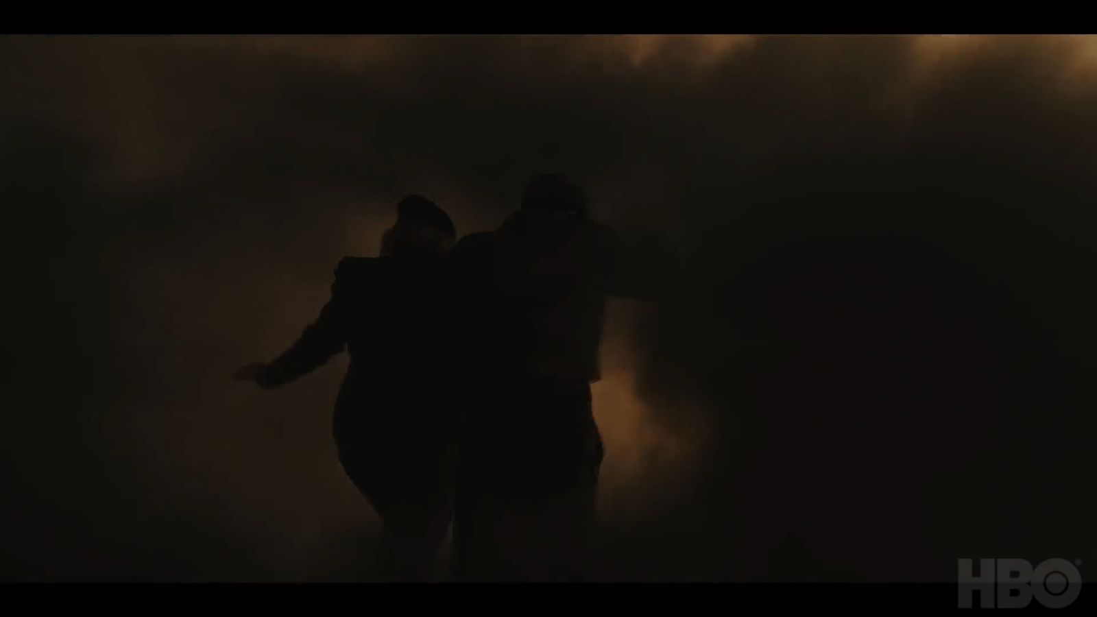 two people standing in the dark with their arms around each other