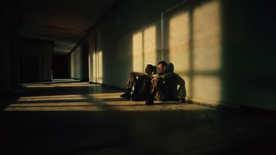 two people sitting on a bench in a hallway