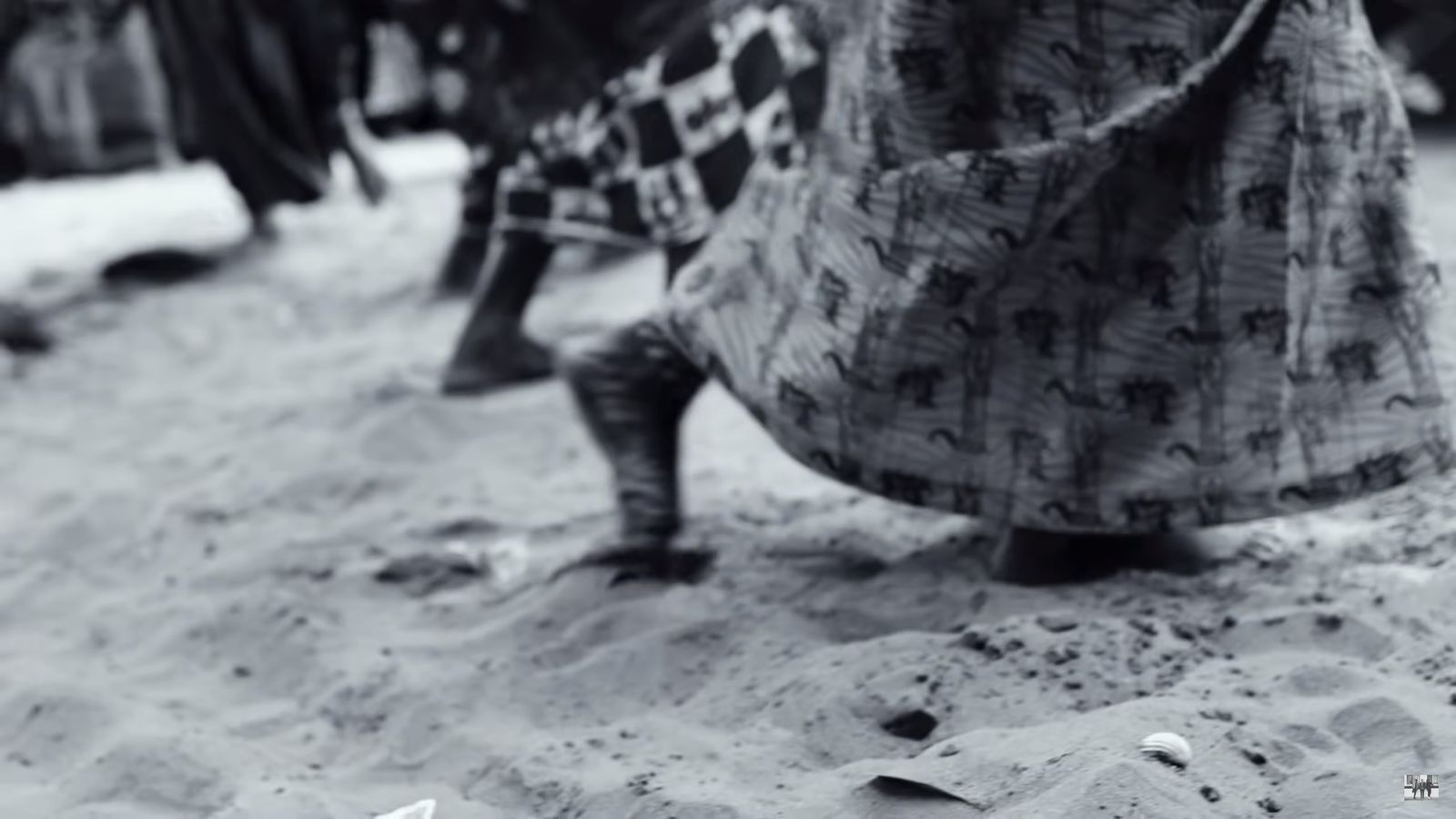 a black and white photo of a person walking in the sand