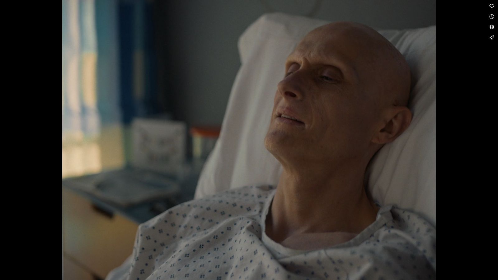 a bald man laying in a hospital bed