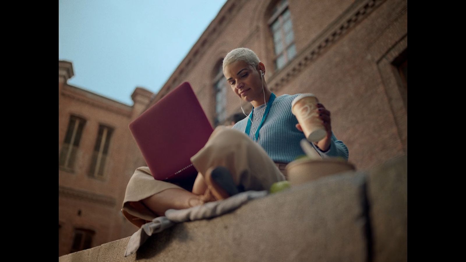 a woman sitting on a ledge using a laptop computer