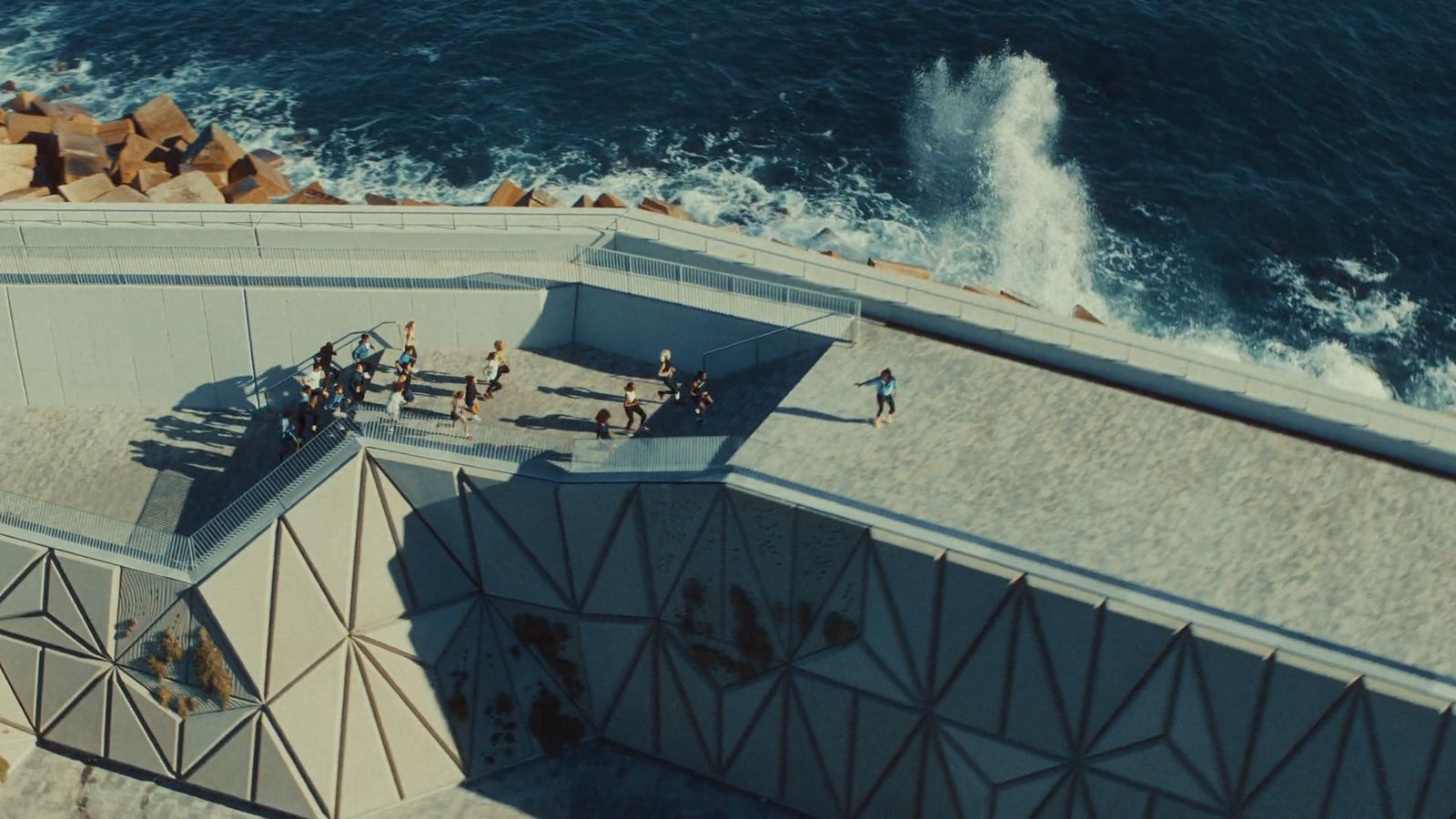 a group of people standing on top of a roof next to the ocean