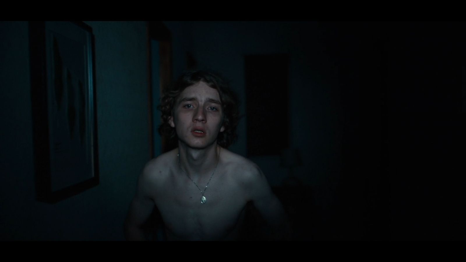 a shirtless man standing in a dark room