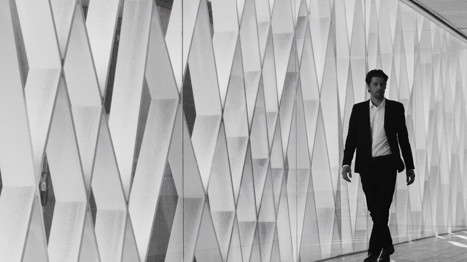 a man walking down a hallway next to a wall