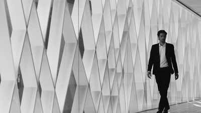 a man walking down a hallway next to a wall