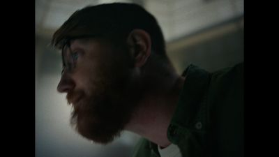 a man with a beard and glasses looking off into the distance