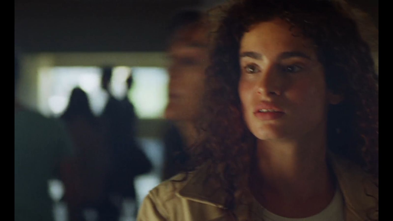 a woman with curly hair standing in front of a group of people