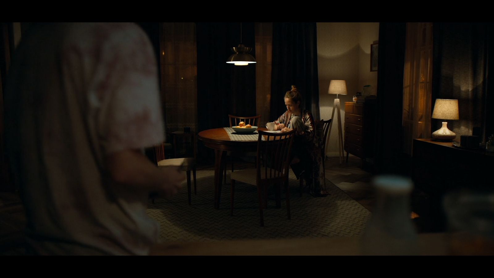 a woman sitting at a table in a dark room