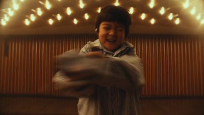 a young boy standing in front of a wall covered in lights