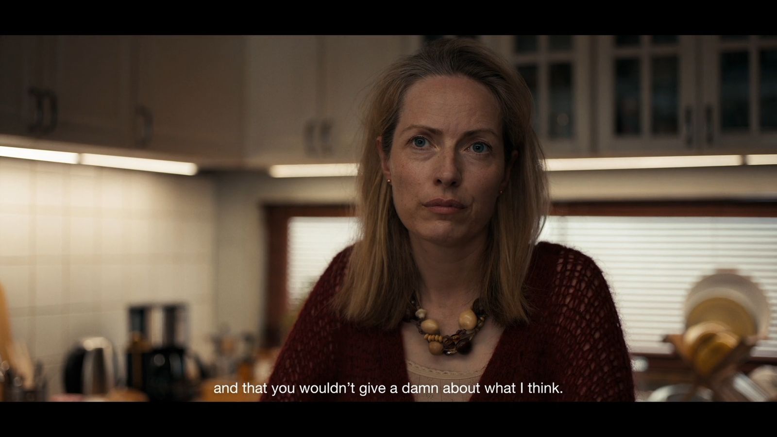 a woman standing in a kitchen looking at the camera