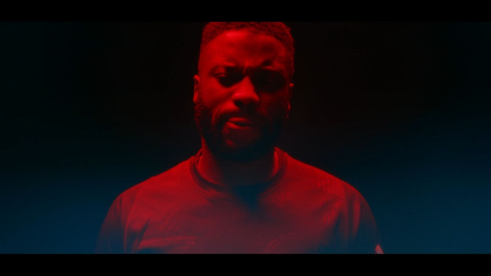 a man in a red shirt standing in the dark