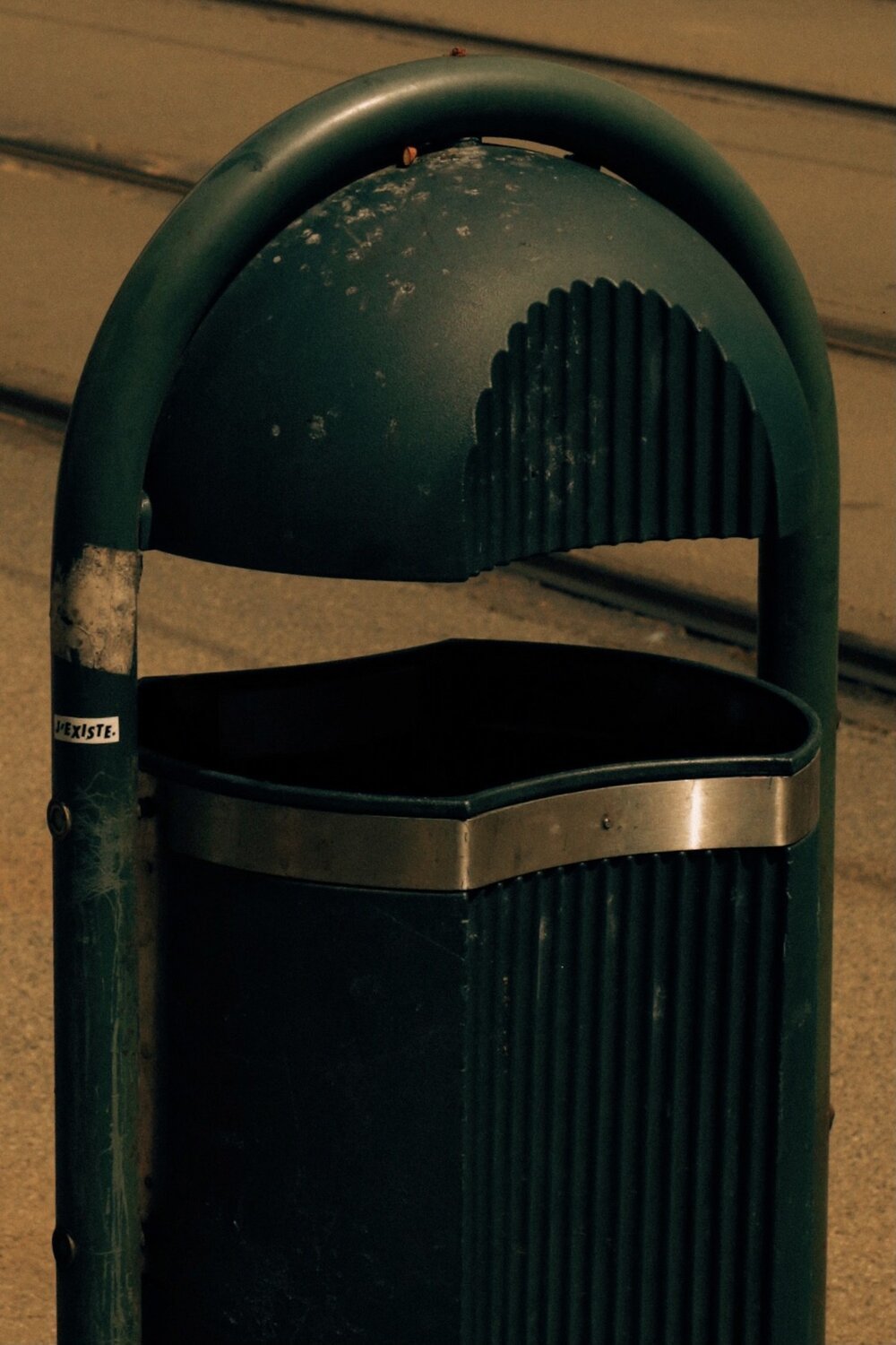 a green trash can sitting on the side of a road