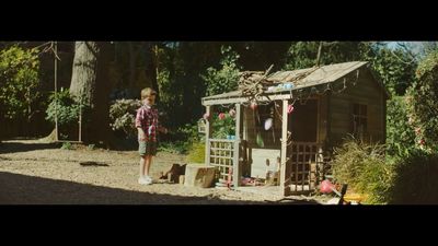 a little boy standing in front of a shed