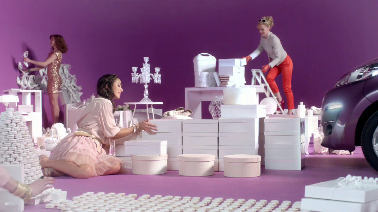 a woman sitting on the ground next to a purple car