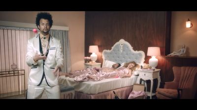 a man standing in front of a bed in a bedroom