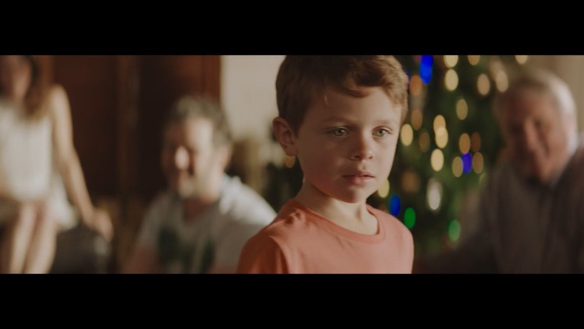 a young boy standing in front of a christmas tree