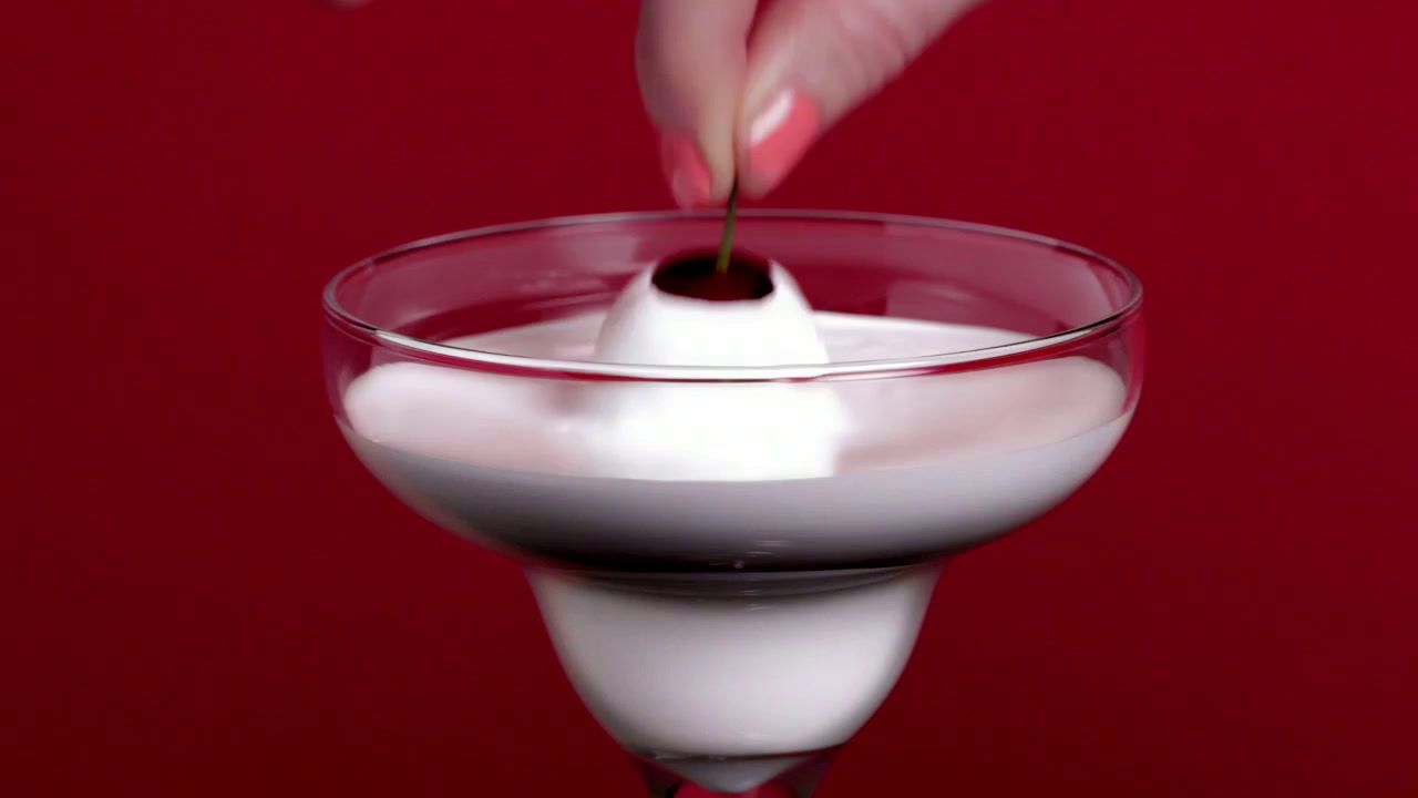 a person dipping a spoon into a glass of milk