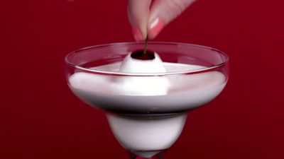 a person dipping a spoon into a glass of milk