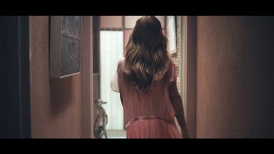 a woman in a pink dress walking down a hallway