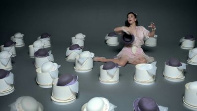 a woman sitting on top of a pile of white hats