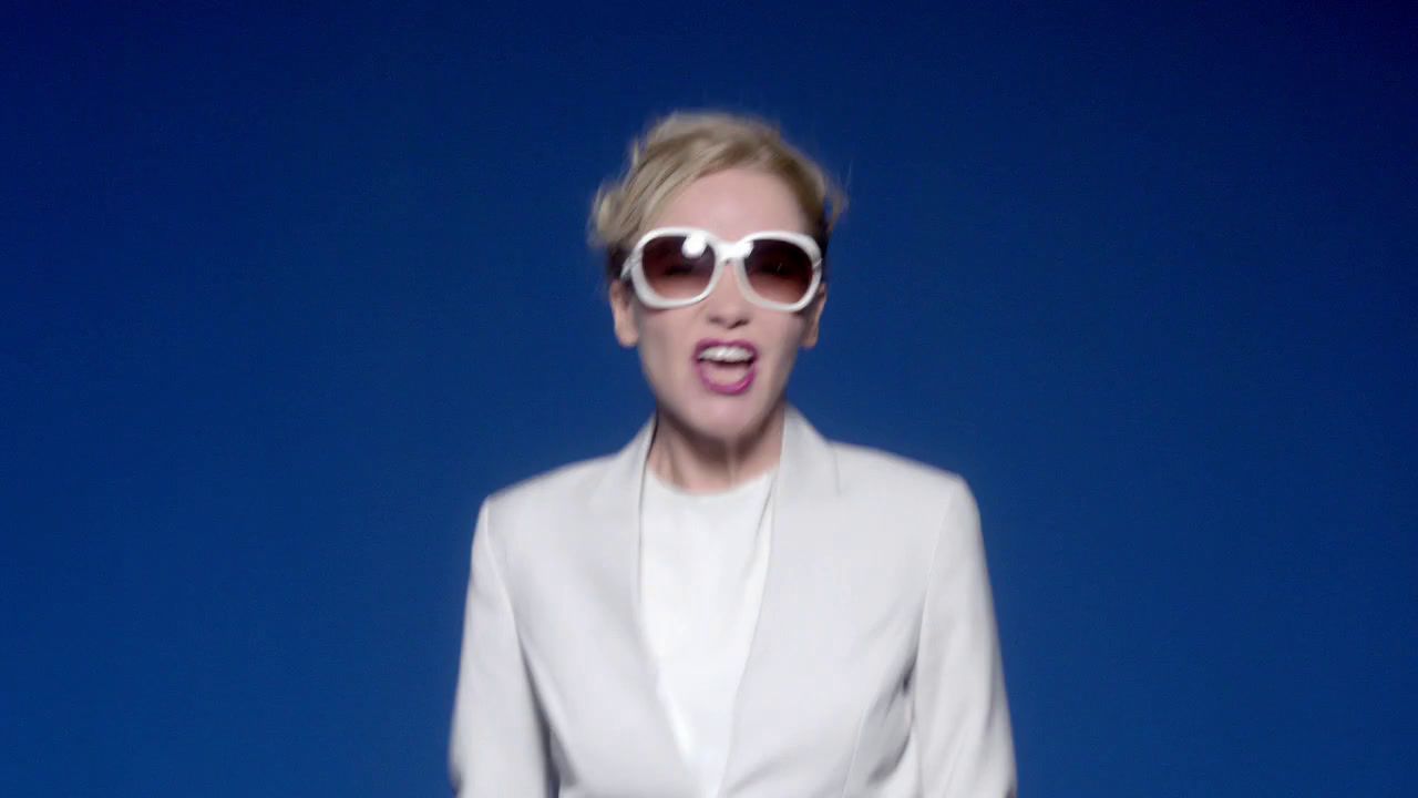 a woman in a white suit and sunglasses making a funny face