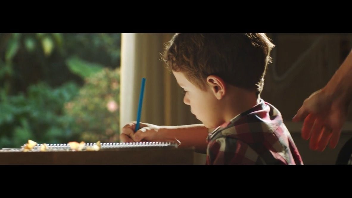 a young boy is writing on a notepad