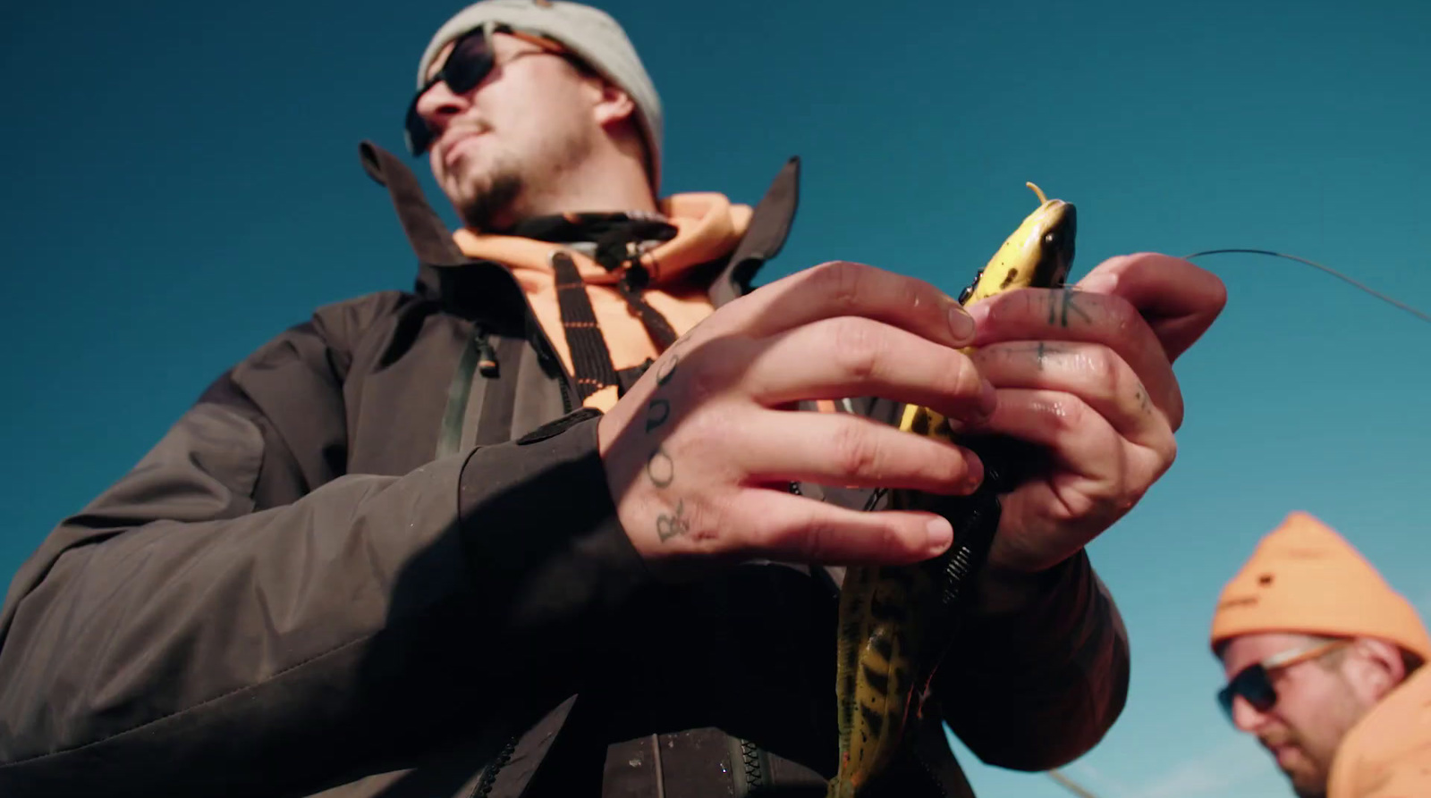 a man holding a fish while standing next to another man