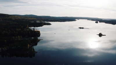 a body of water surrounded by trees and clouds