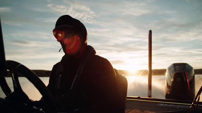 a man sitting in the back of a boat on a body of water