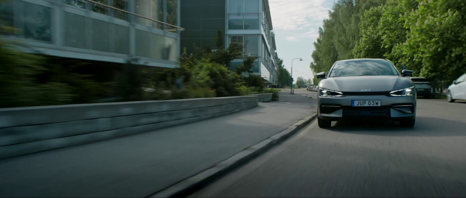 a silver car driving down a street next to tall buildings