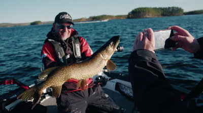 a man holding a fish while sitting on a boat