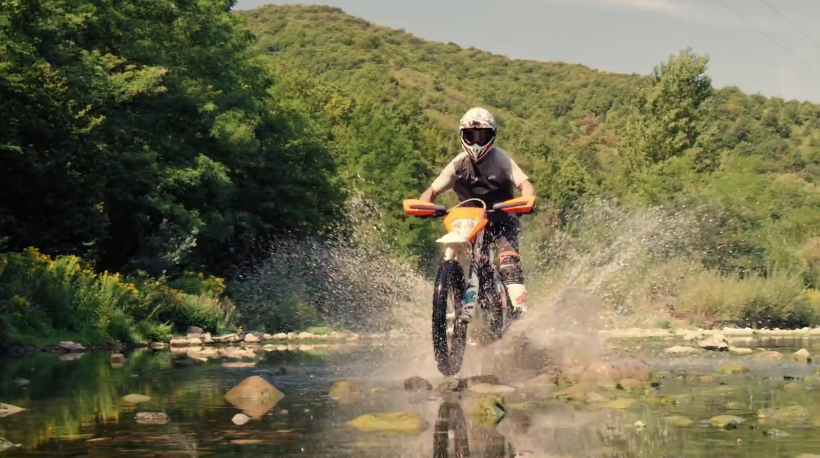 a man riding a dirt bike across a river